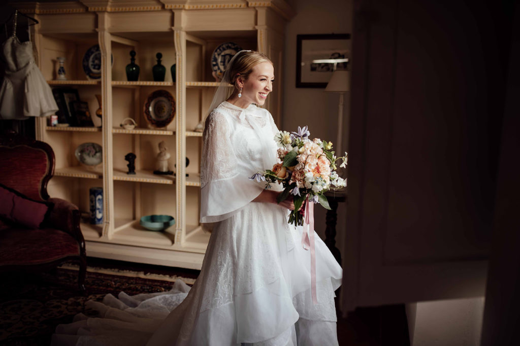 A bride looks out of the window smiling. Villa Il Pozzo Tuscany