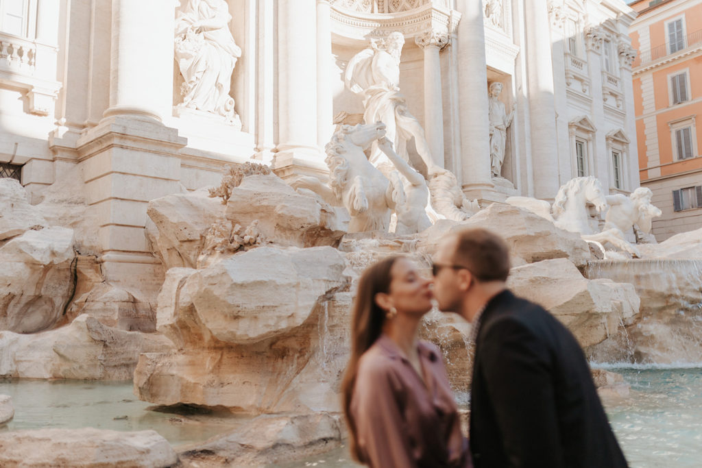 a couple kiss in front of the Trevi fountain in rome
